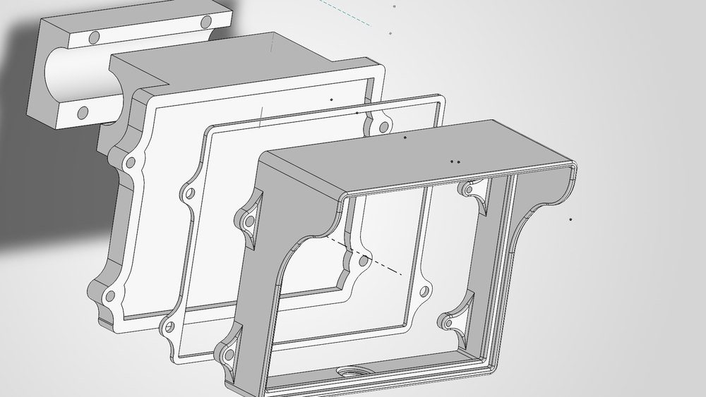Exploded view of the driver dash housing: a tube-clamp bracket, the housing body and the front bezel, separated along their assembly axis.