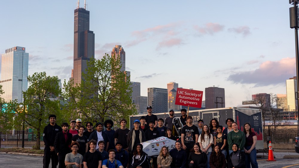 The UIC Society of Automotive Engineers team photographed with the car in front of the Chicago skyline.
